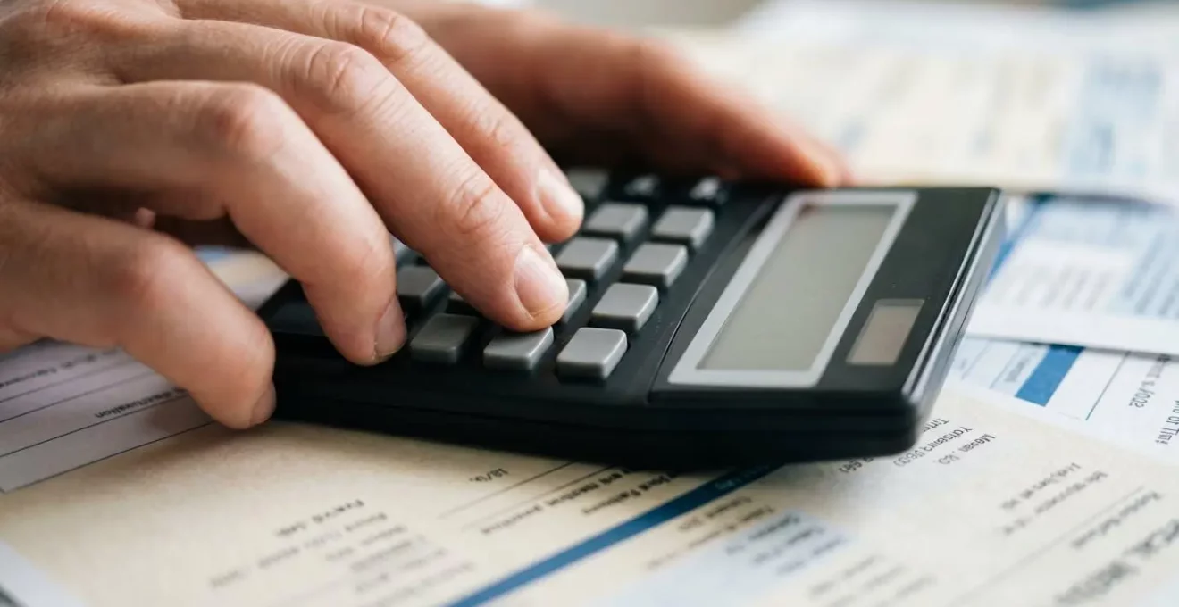 Gros plan sur des mains utilisant une calculatrice avec des documents de santé