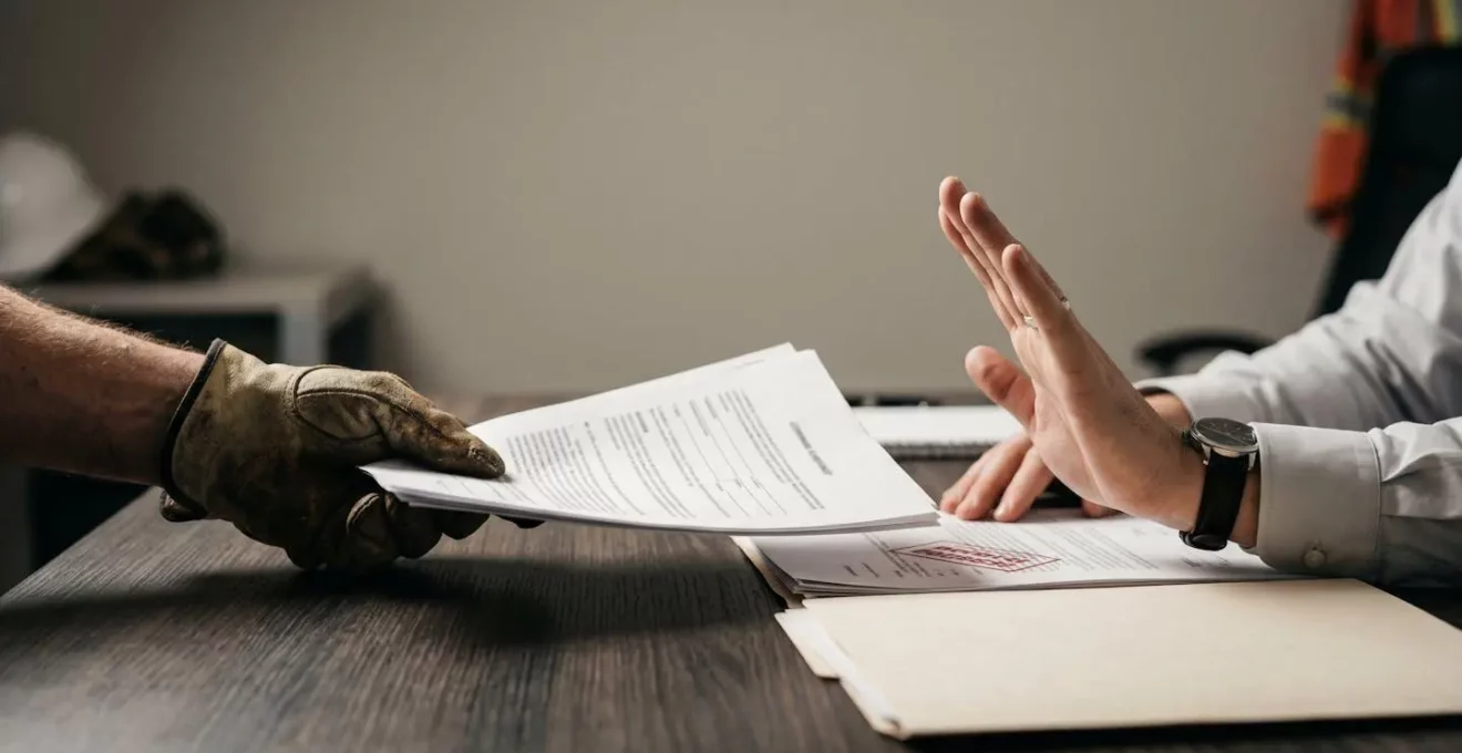Scène symbolisant le risque d'exclusion de garantie avec des documents officiels et un geste de refus