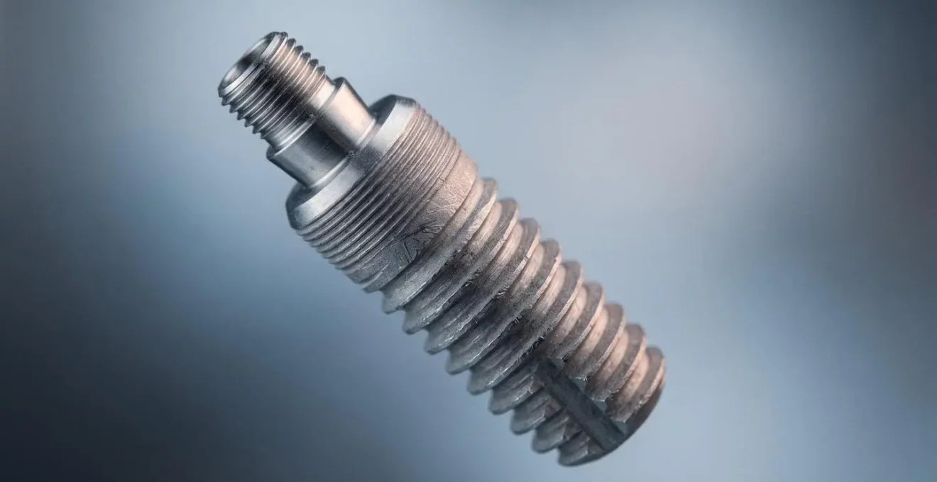 Gros plan macro d'un implant dentaire en titane révélant sa texture et sa structure microscopique